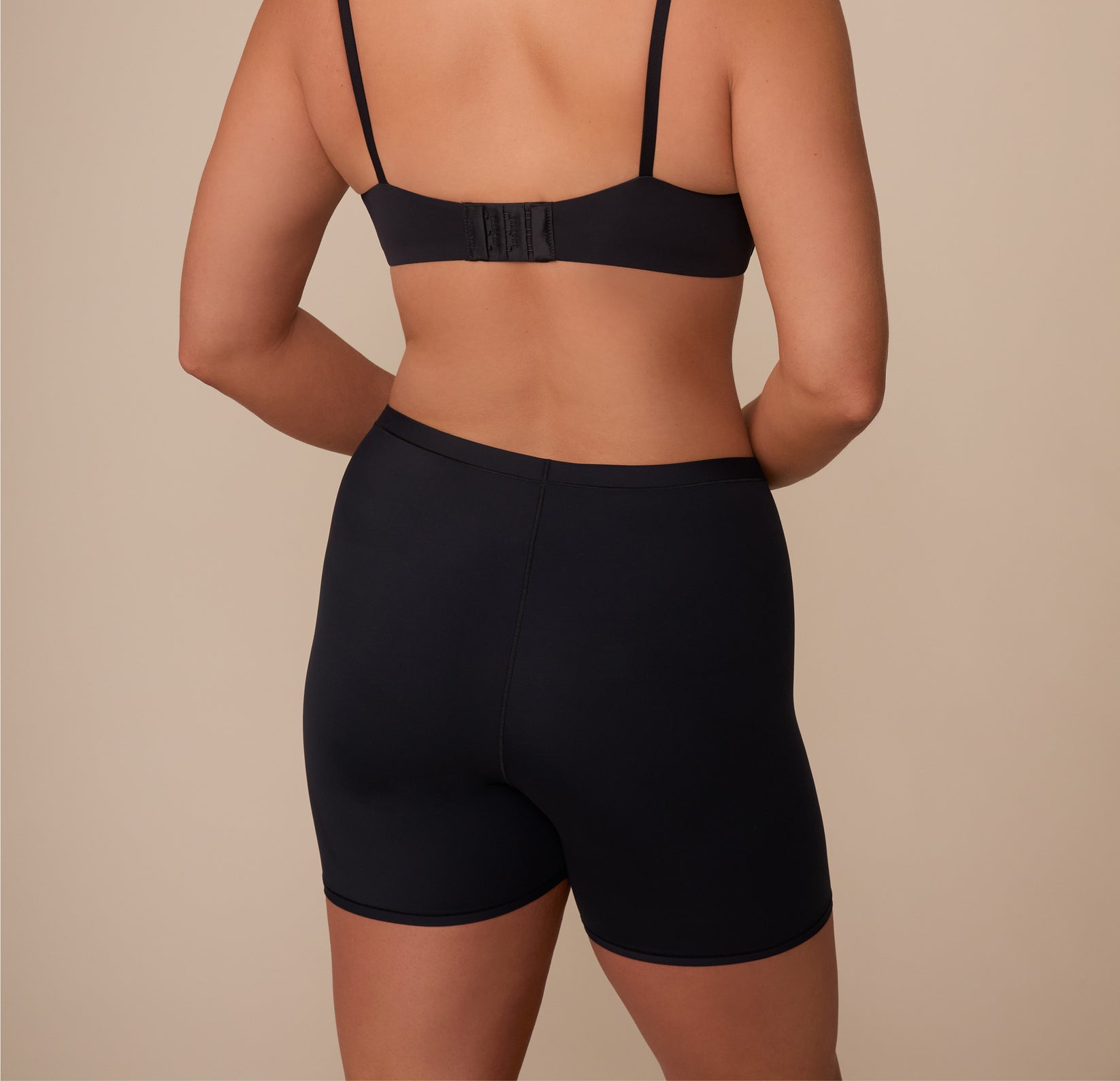 Back view of Sonnie in the Bliss Under Short in Black, highlighting the clean seam lines and flexible fit that moves with the body.