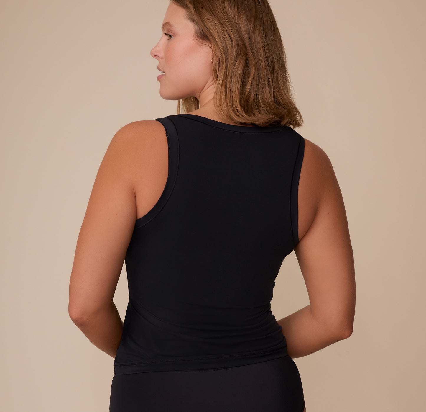 Back view of Sonnie in the Bliss Tank in Black, showcasing full back coverage and clean stitching at the armholes.