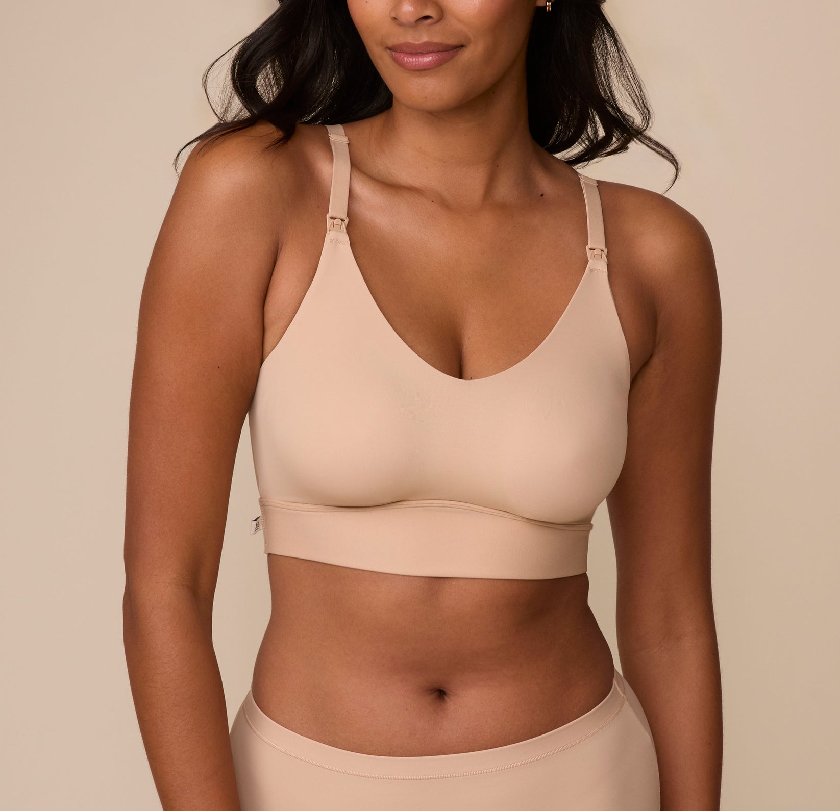 Victoria wears the Bliss Nursing Bralette in Beige, showcasing its smooth, seamless design with a deep V-neckline. The wide underband provides gentle support, while adjustable straps ensure a customizable fit. sizing: Victoria wears size Medium