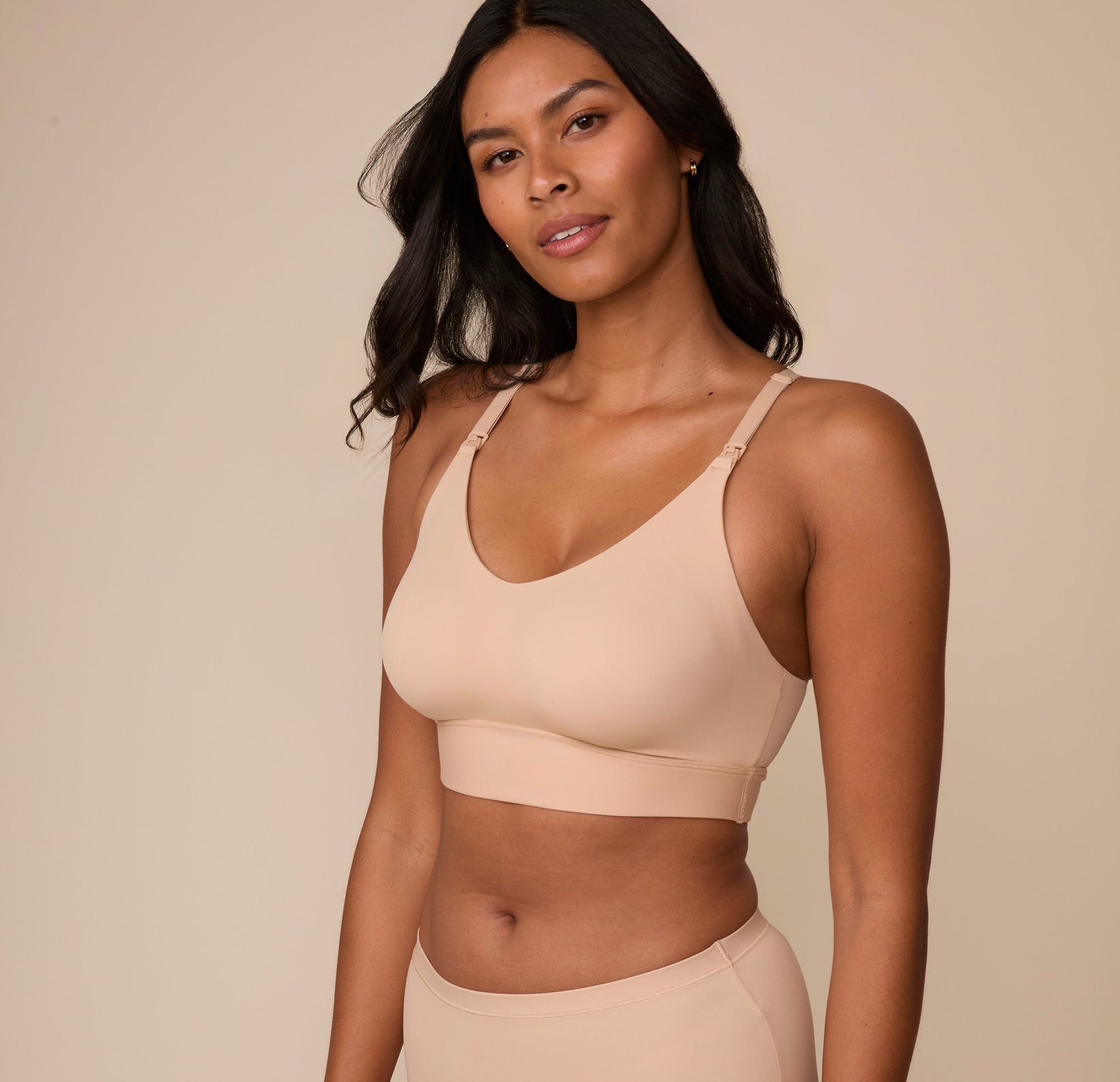 Victoria poses at a three quarter angle in the Bliss Nursing Bralette in Beige, offering a side view that emphasizes the soft, stretchy fabric and supportive design.