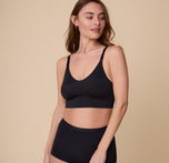 Gracie poses in the Bliss Nursing Bra in Black, highlighting the smooth, wireless design with clip-down nursing straps for convenience.