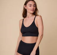 Gracie poses in the Bliss Nursing Bra in Black, highlighting the smooth, wireless design with clip-down nursing straps for convenience.