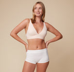 Megan wearing the Bliss Plunge Adjustable Bralette and Lounge Rib Boyshort in White, standing with hands on hips and facing forward.