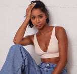 Ally wearing the Bliss Plunge Adjustable Bralette in Rose, styled with jeans in a casual sitting pose.