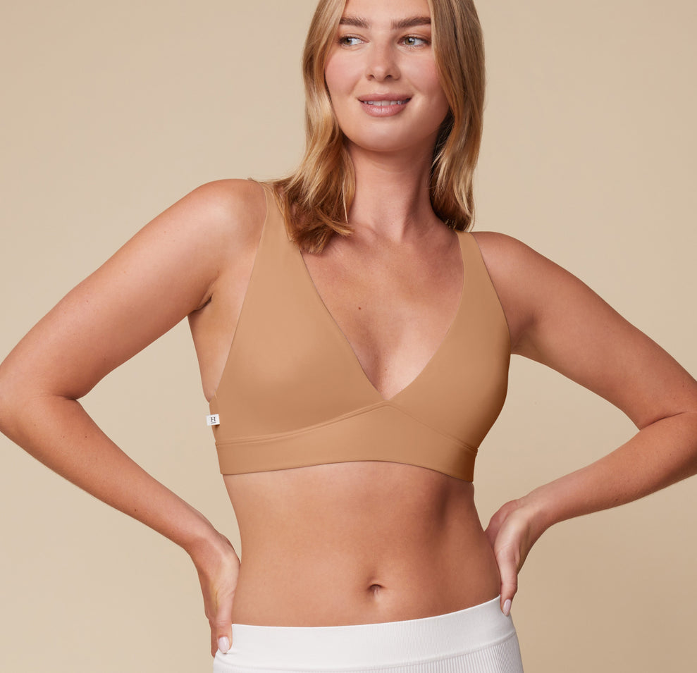 Megan wearing the Bliss Plunge Adjustable Bralette in Tan with a front view, hands on hips. sizing: Megan wears size Medium. Sizes L-4XL have higher center in front for additional support.