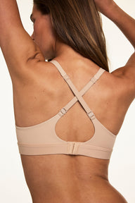 Back view of Darion wearing the Bliss Plunge Adjustable Bra in Beige, highlighting the adjustable crisscross straps, hook-and-eye closure, and keyhole back detail.