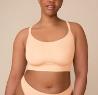 Front view of Zarria wearing the Bliss Racerback Bralette in Daybreak. The image highlights the smooth scoop neckline and soft, molded cups for wire-free support. sizing: Zarria wears size XL