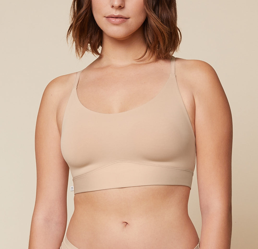A close-up side view of Carli, focusing on her upper body. She is wearing the Bliss Racerback Bralette in Beige, showcasing the design and fit of the bralette. sizing: Carli wears size Medium