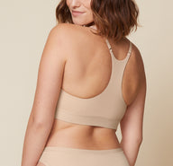Carli is shown from the back, wearing the Bliss Racerback Bralette. The smooth racerback material and adjustable straps are emphasized.