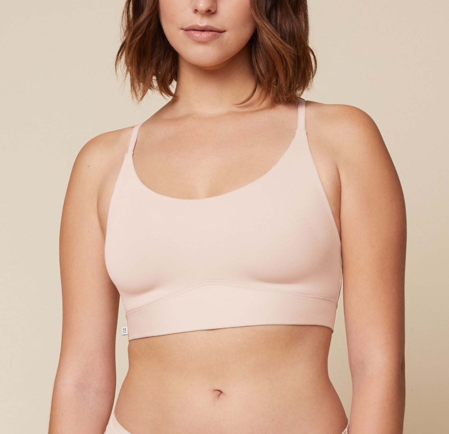 Carli standing with her arms raised, wearing the Bliss Racerback Bralette. The front view highlights the comfortable and relaxed fit of the bralette. sizing: Carli wears size Medium
