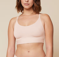 Carli standing with her arms raised, wearing the Bliss Racerback Bralette. The front view highlights the comfortable and relaxed fit of the bralette. sizing: Carli wears size Medium