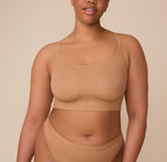 Zarria stands confidently facing the camera, wearing the Bliss Racerback Bralette and Bliss Highwaist Thong in Tan. The scoop neckline and wide band of the bralette pair with the high-rise thong’s soft microfiber fabric, offering comfort and a seamless look. sizing: Zarria wears size XL