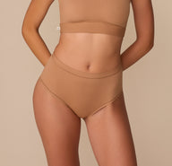 Alexis models the Bliss Highwaist Brief in Tan, showcasing the high-rise silhouette with smooth, seamless edges for an invisible fit under clothes. sizing: Alexis wears size Small