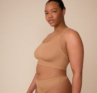 Side profile of Zarria in the Bliss Racerback Bralette and Bliss Highwaist Thong in Tan. The image highlights the thong’s high waistline and the racerback bralette’s supportive straps and smoothing fabric.