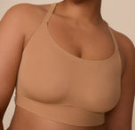 Close up view of Zarria in the Bliss Racerback Bralette in Tan. The outside tag and wide band are emphasized. 