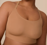 Close up view of Zarria in the Bliss Racerback Bralette in Tan. The outside tag and wide band are emphasized. 