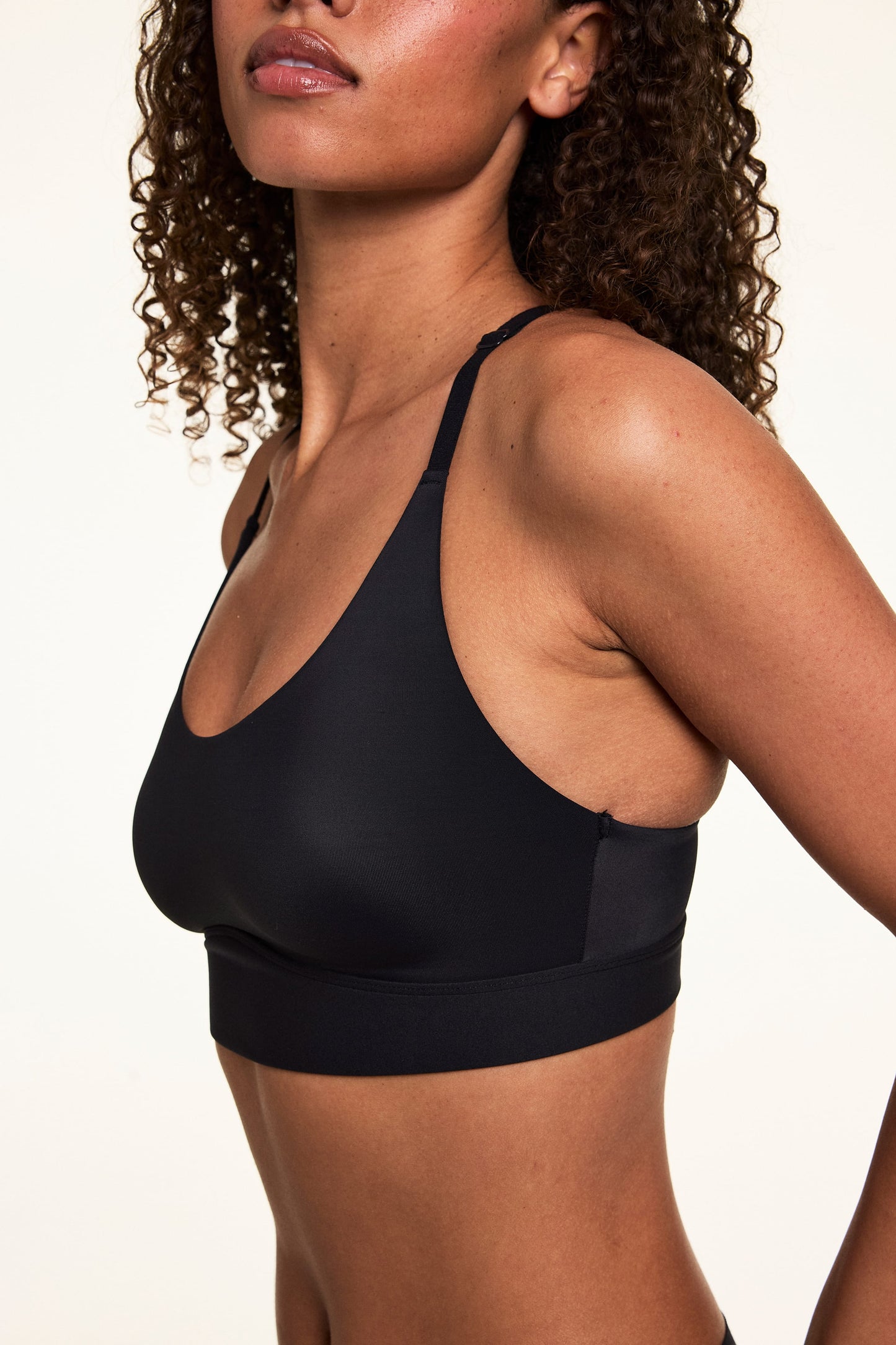 Side-angle view of Courtney wearing the Bliss Racerback Bralette in Black, showing the scoop neckline, soft fabric, and wide underband.