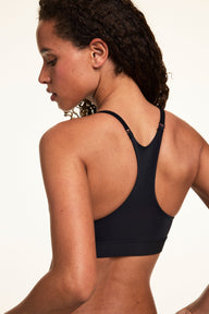 Back three-quarter view of Courtney wearing the Bliss Racerback Bralette in Black, highlighting the racerback design and adjustable straps.