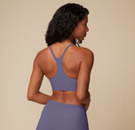 Ally is seen from behind, modeling the Bliss Racerback Bralette in Overcast. The racerback cut and adjustable straps provide stability and functionality. 