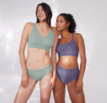 Anna and Ally pose together, wearing Bliss bralettes in complementary shades. Ally wears the Bliss Racerback Bralette in Overcast, while Anna wears the original Bliss Bralette in Seaglass, showcasing versatility in style and fit.
