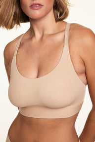 Close-up front view of Sonnie wearing the Bliss Racerback Bralette in Beige, showing the scoop neckline, lightweight fabric, and thin adjustable straps.