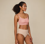 Side view of Zoe standing tall with one hand resting on her thigh, wearing the Bliss Scoop Bralette in Dusty Rose and Bliss Highwaist Brief in Beige, emphasizing the smooth, comfortable fit.
