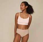 Zoe standing with hands resting at her sides, wearing the Bliss Scoop Bralette in Rose and the Bliss Highwaist Brief in Beige. She faces forward, smiling softly, showcasing the comfortable fit of both pieces. sizing: Zoe wears size Small