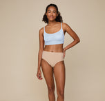 Full-body image of Zoe standing confidently, hand on her hip, in the Bliss Scoop Bralette in Tidal and Bliss Highwaist Brief in Beige, showcasing the comfortable fit of the matching set.