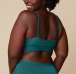 Back view of Akesha in the Bliss Scoop Bralette and highwaist briefs in Everglade. She looks over her shoulder, showcasing the adjustable straps of the bralette.