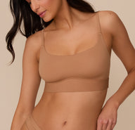 Marcela wearing the Bliss Scoop Bralette in Tan, shown from the front at a slight angle. The scoop neckline and smooth fabric create a clean, minimal look. sizing: Marcela wears size Small