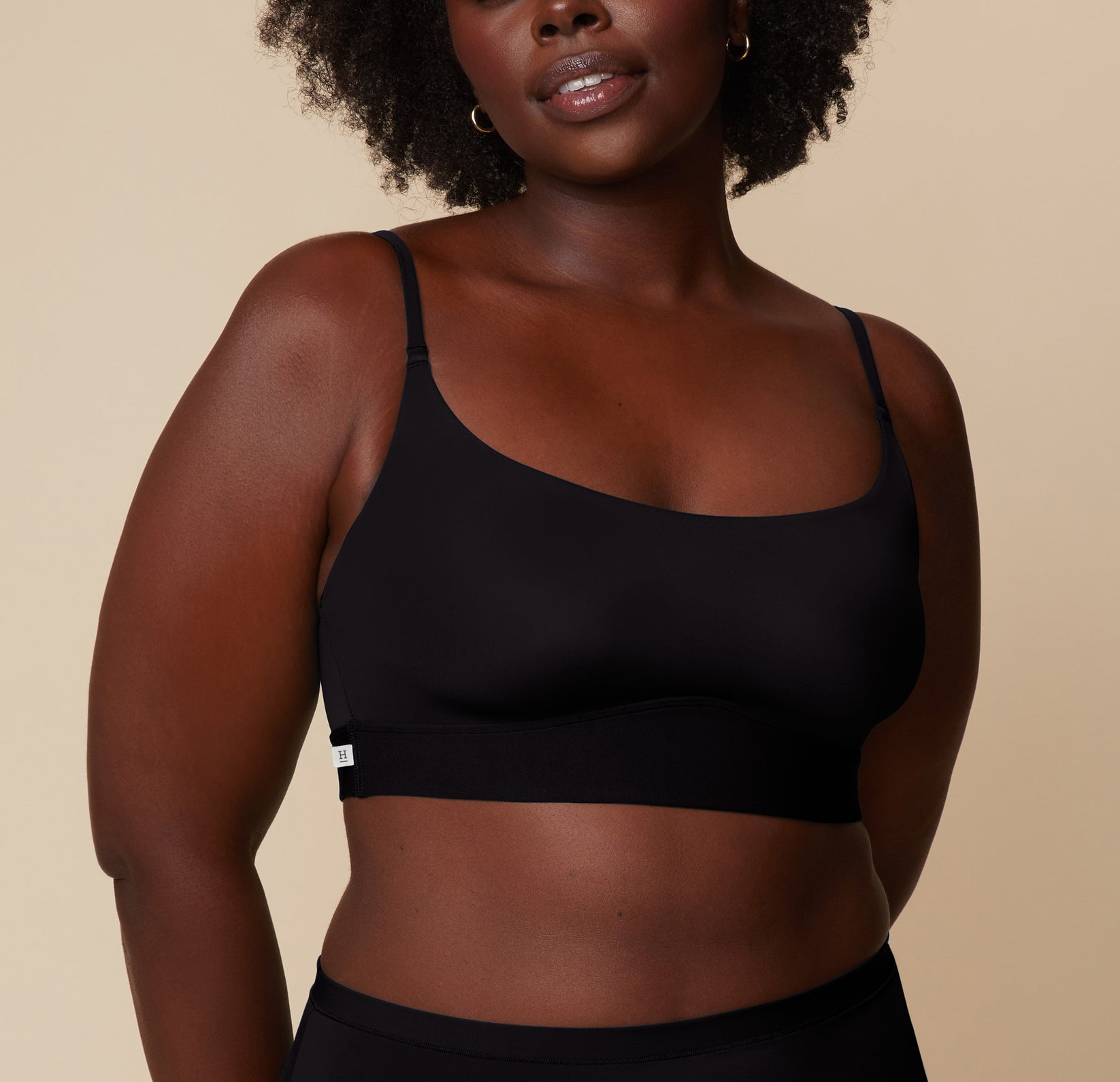 Akesha wearing the Bliss Scoop Bralette in Black, smiling slightly. The image highlights the smooth, wireless construction and soft finish. sizing: Akesha wears size Large