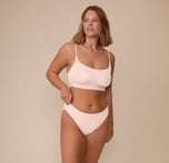 Full-body shot of Sonnie wearing the Bliss Scoop Bralette and matching Bliss Bikini in Rose. The image captures the soft, supportive fit of the tonal set.