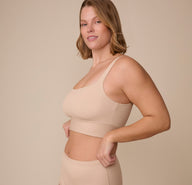 Sonnie stands at an angle, smiling slightly while showcasing the Bliss Square Neck Bralette's smooth, supportive fit with its longline band and squared-off neckline.