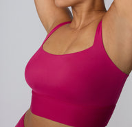 Angled close-up on a white studio backdrop of a model wearing the Bliss Square Neck Bralette in Winterberry, showing the clean square neckline and soft, lightly lined cups.