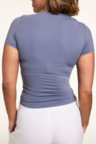 Back view of Sonnie wearing the Bliss T-Shirt in Steel with white lounge pants, featuring the smooth back, short sleeves, and fitted silhouette.