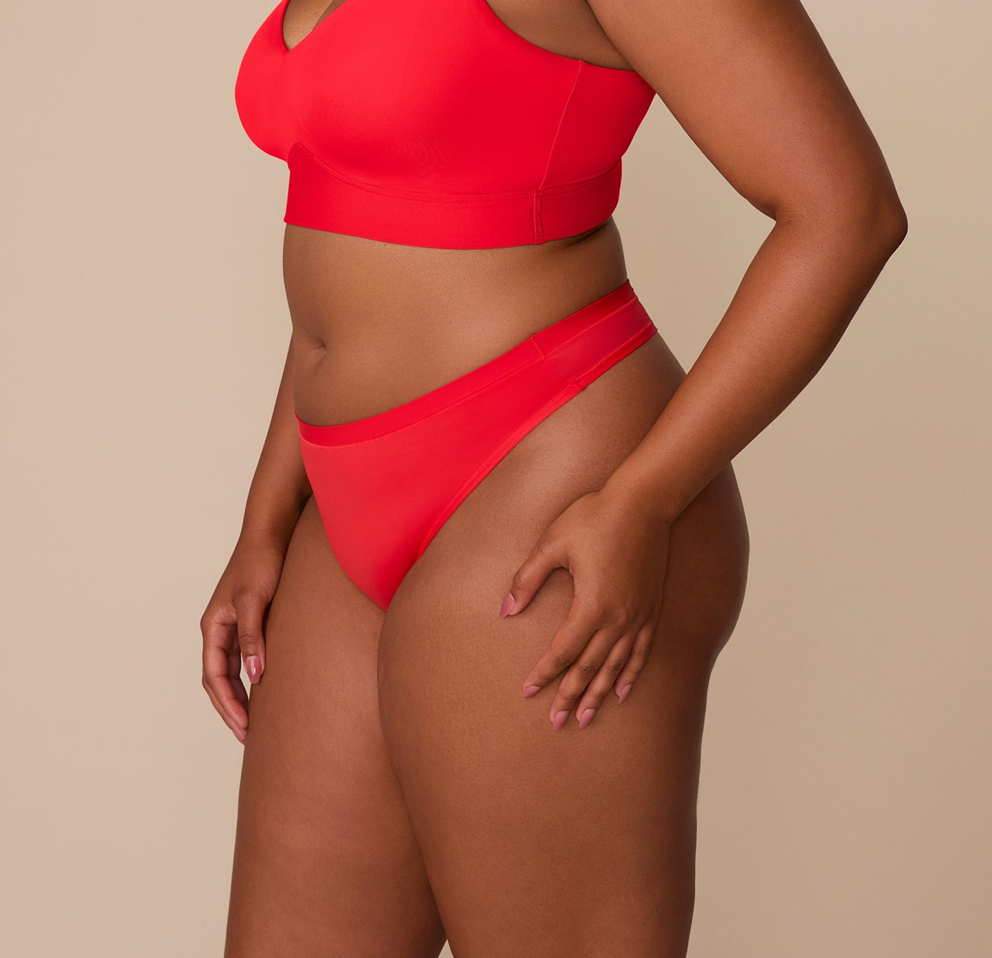 Side view of Zarria in the Bliss Thong in Cherry. The image emphasizes the clean lines, minimal seam leg openings, and soft waistband that stays in place.