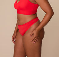 Side view of Zarria in the Bliss Thong in Cherry. The image emphasizes the clean lines, minimal seam leg openings, and soft waistband that stays in place.