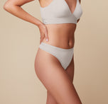 Side view of Megan wearing the Bliss Triangle Bralette and Bliss Thong in Frost. The image highlights the thong’s high-cut leg opening and stretchy, smoothing waistband.