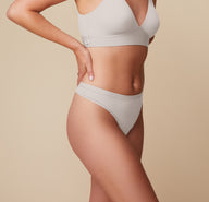 Side view of Megan wearing the Bliss Triangle Bralette and Bliss Thong in Frost. The image highlights the thong’s high-cut leg opening and stretchy, smoothing waistband.