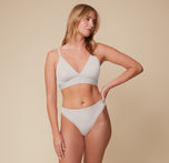 Megan standing in a relaxed pose wearing the Bliss Triangle Bralette and Bliss Thong in Frost. This full-body shot showcases the sleek fit and lightweight construction of the thong.
