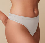 Close-up of the Bliss Thong in Frost on Megan. The detail image emphasizes the soft stitching and elastic-free edge for dig-free comfort and a seamless look under clothes.