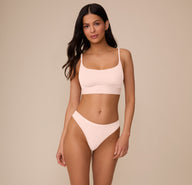 Full front view of Marcela wearing the Bliss Thong and Bliss Scoop Bralette, both in Rose. The set highlights the soft, lightweight microfiber fabric and minimal, everyday design.