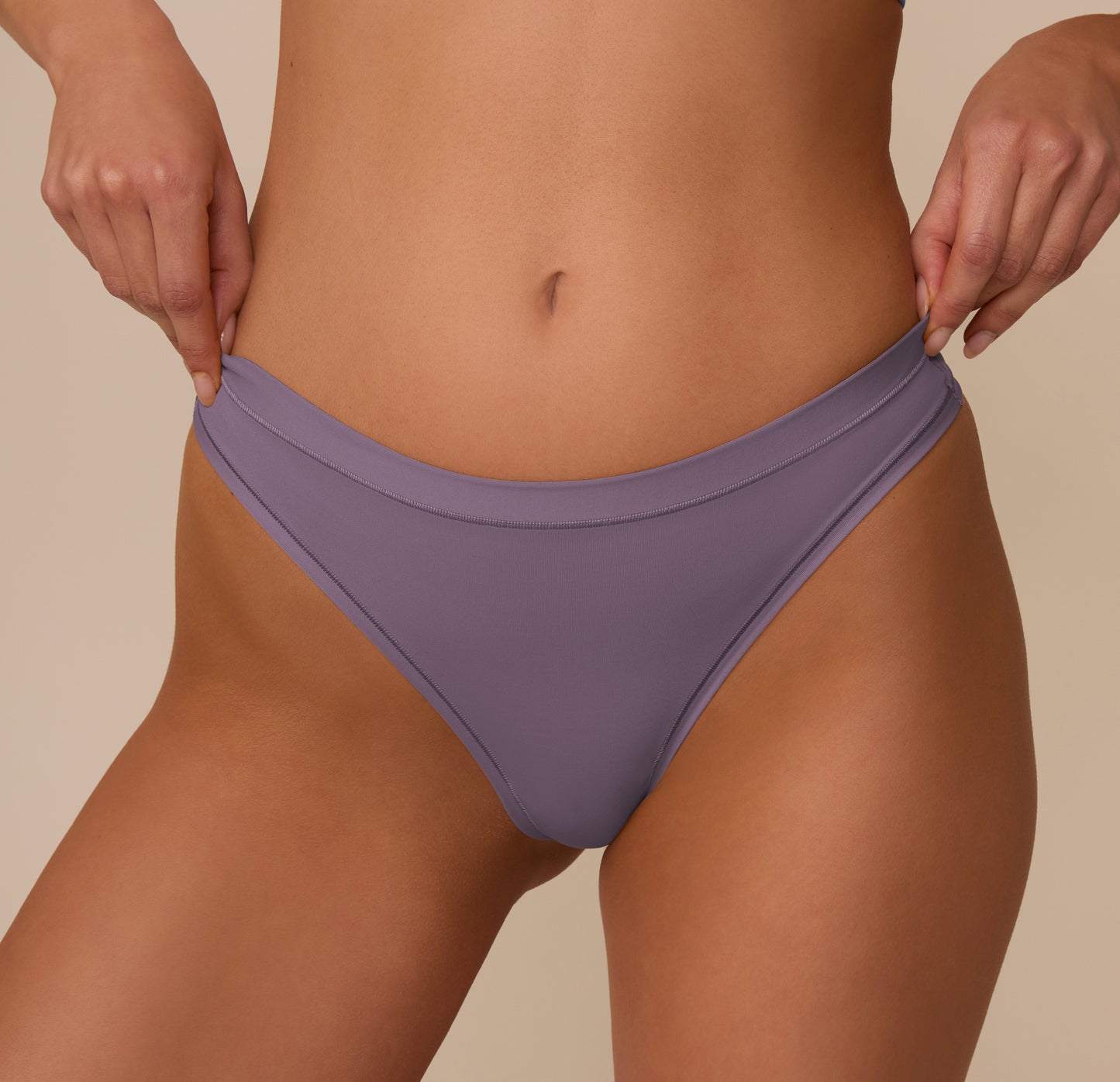 Close-up of the Bliss Thong in Eclipse worn by Marcela, focusing on the waistband detail and seamless side construction for a no-show fit beneath clothing.