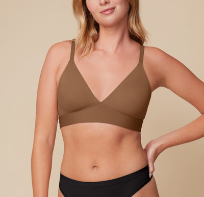 Megan stands facing forward, wearing the Bliss Triangle Bralette in Brown and the Bliss Highwaist Thong in Black. The bralette’s plunging neckline and molded cups offer soft lift and wireless support, paired with the high-rise thong for a sleek, smoothing silhouette. sizing: Megan wears size Medium