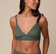 Nemesis wearing the Bliss Triangle Bralette in Fir, front angled view highlighting plunging V-neckline and adjustable straps. sizing: Nemesis wears size Medium