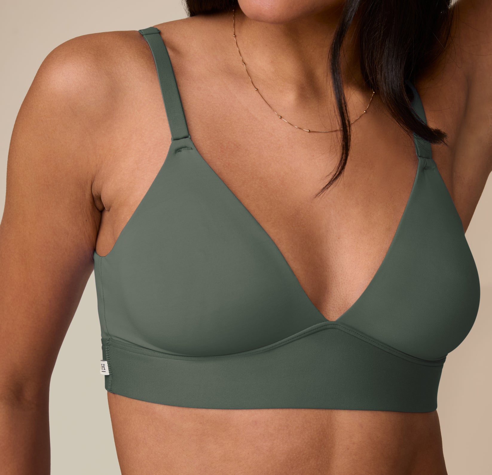 Close-up detail of Nemesis in the Bliss Triangle Bralette in Fir, showing soft stretch fabric and minimalist logo tag.