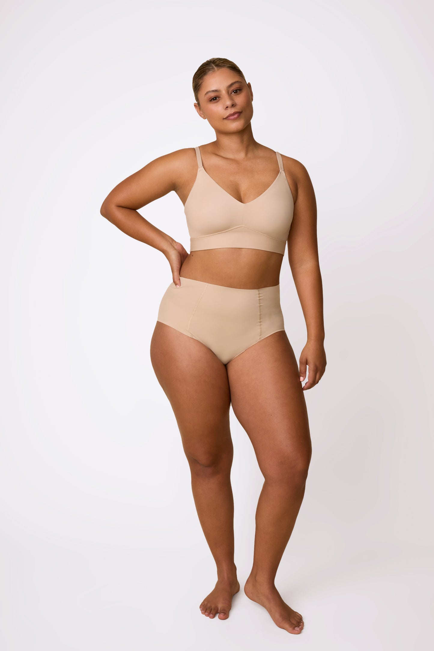 Full-body studio shot on a white backdrop of India wearing the Bliss Triangle Bralette in Beige with the matching brief, showing the clean silhouette, wireless band, and smooth finish.