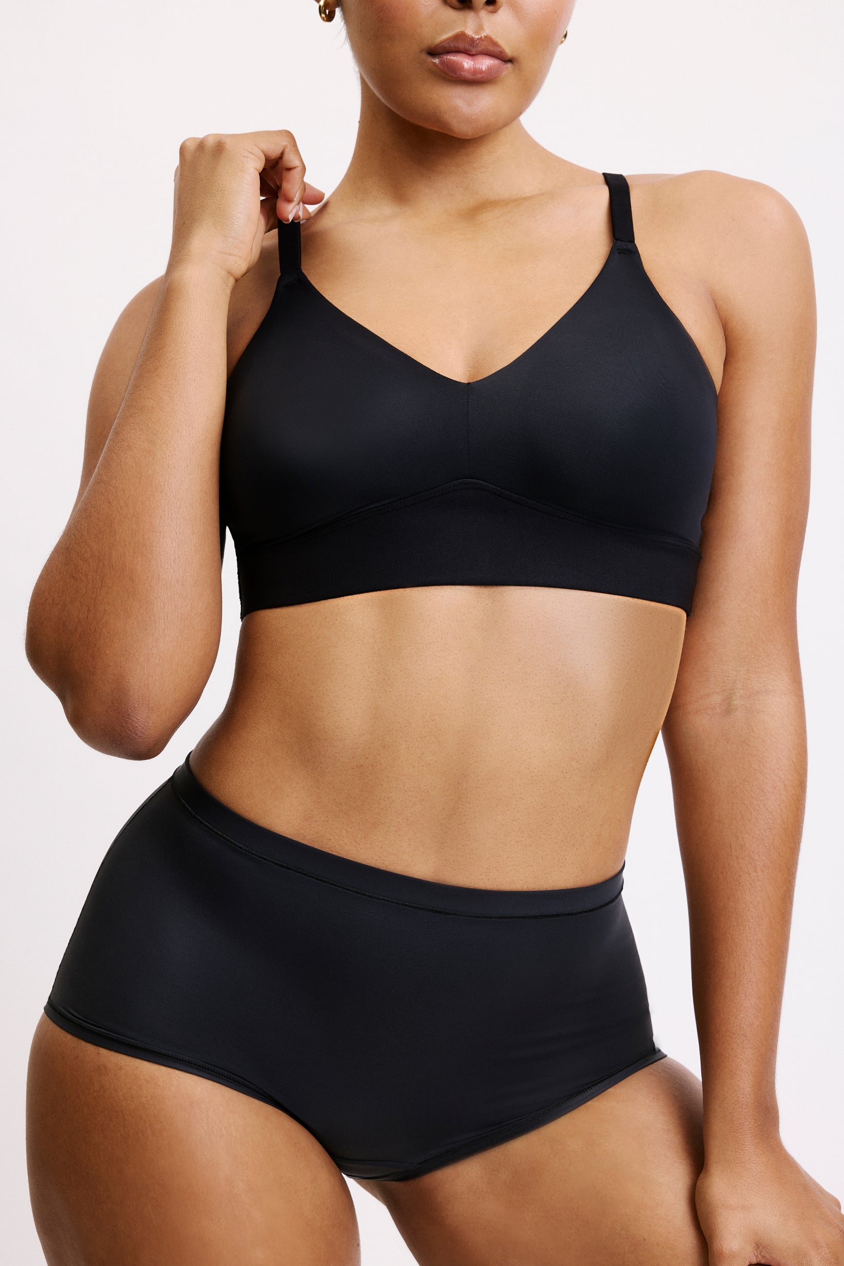 In a close-up studio shot on a white backdrop, Amber wears the Bliss Triangle Bralette in Black with the matching brief, focusing on the deep V front and soft microfiber band.