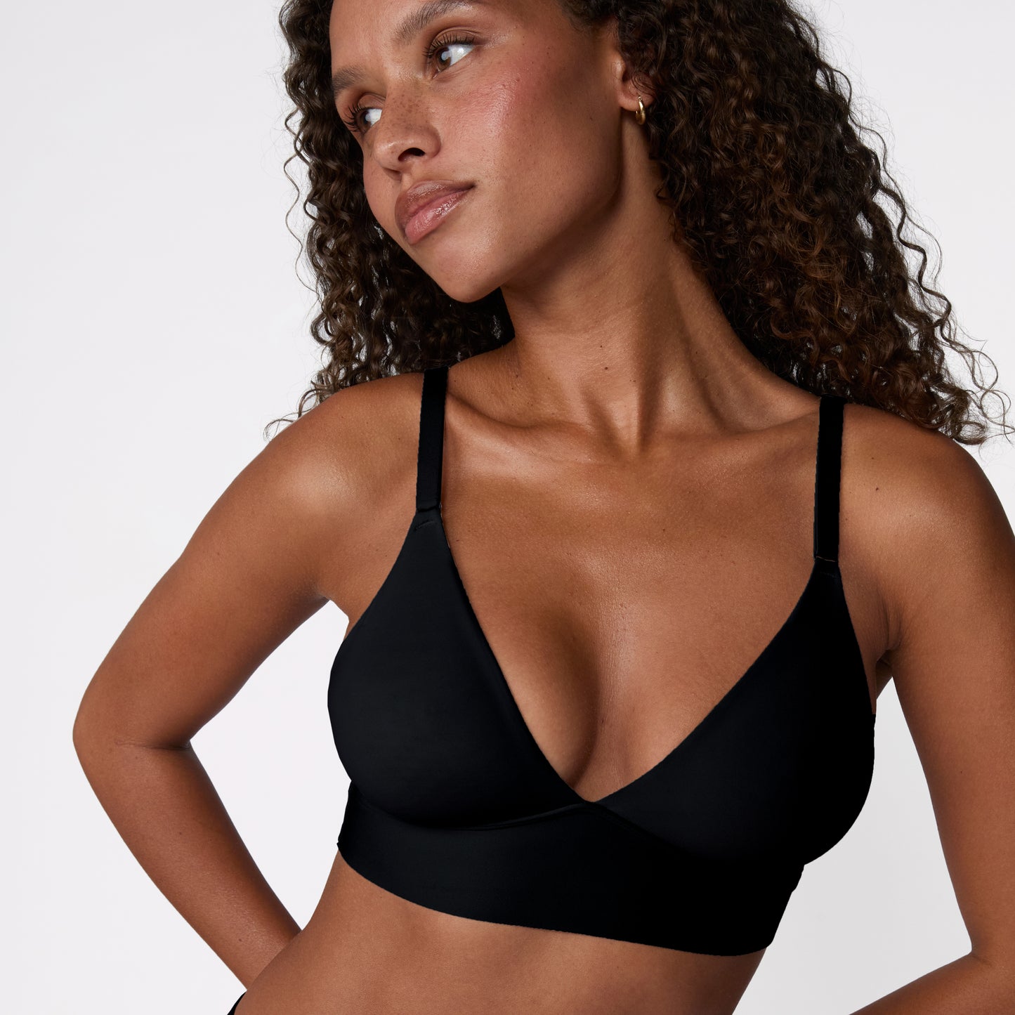 In a white studio setting, Courtney wears the Bliss Triangle Bralette in Black, shown in a close-up to highlight the clean V-neck shape, wireless band, and soft microfiber fabric.