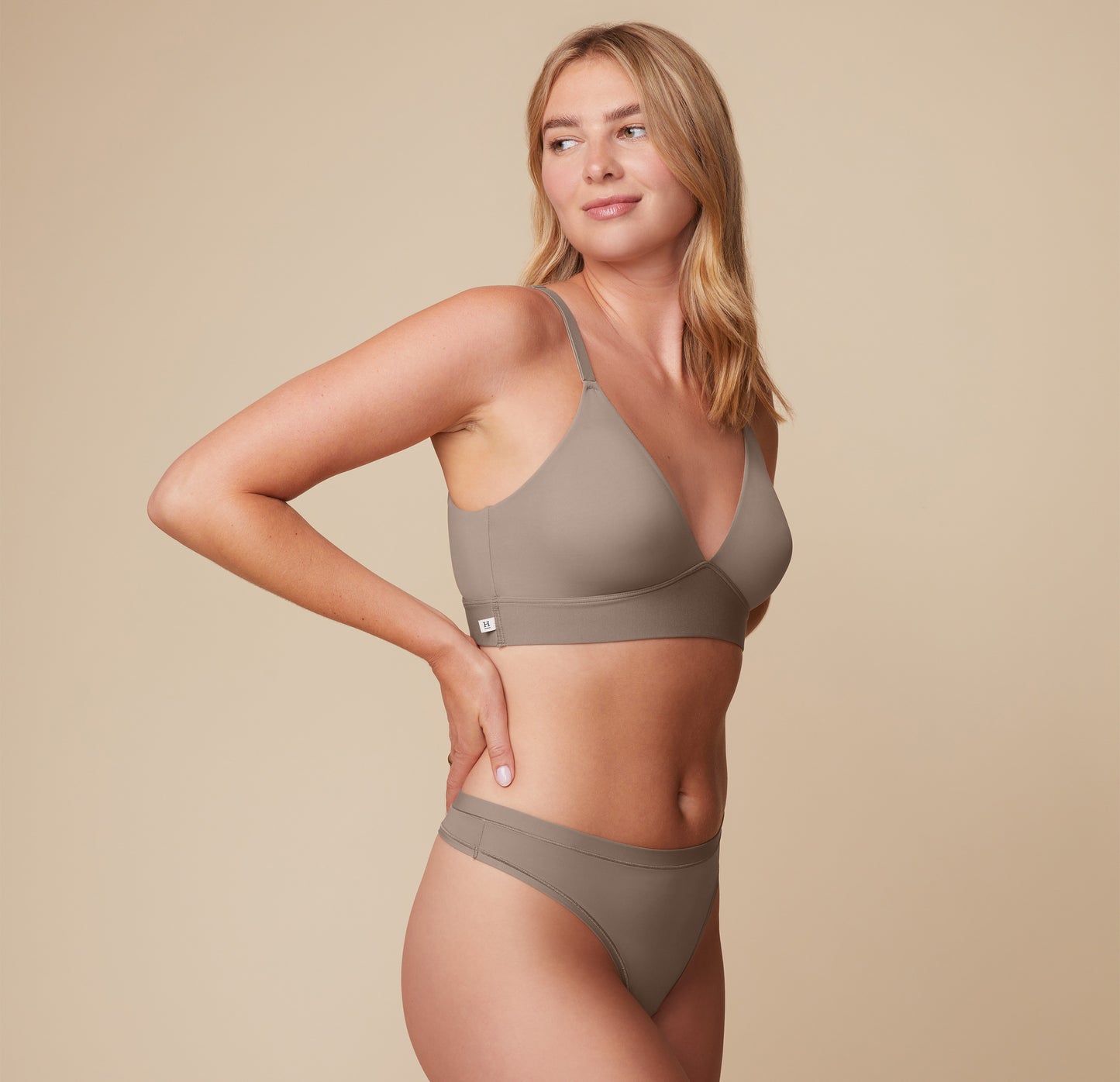 Megan turns slightly to the side, wearing the Bliss Triangle Bralette in Desert. The clean lines and comfortable band create a smooth silhouette.